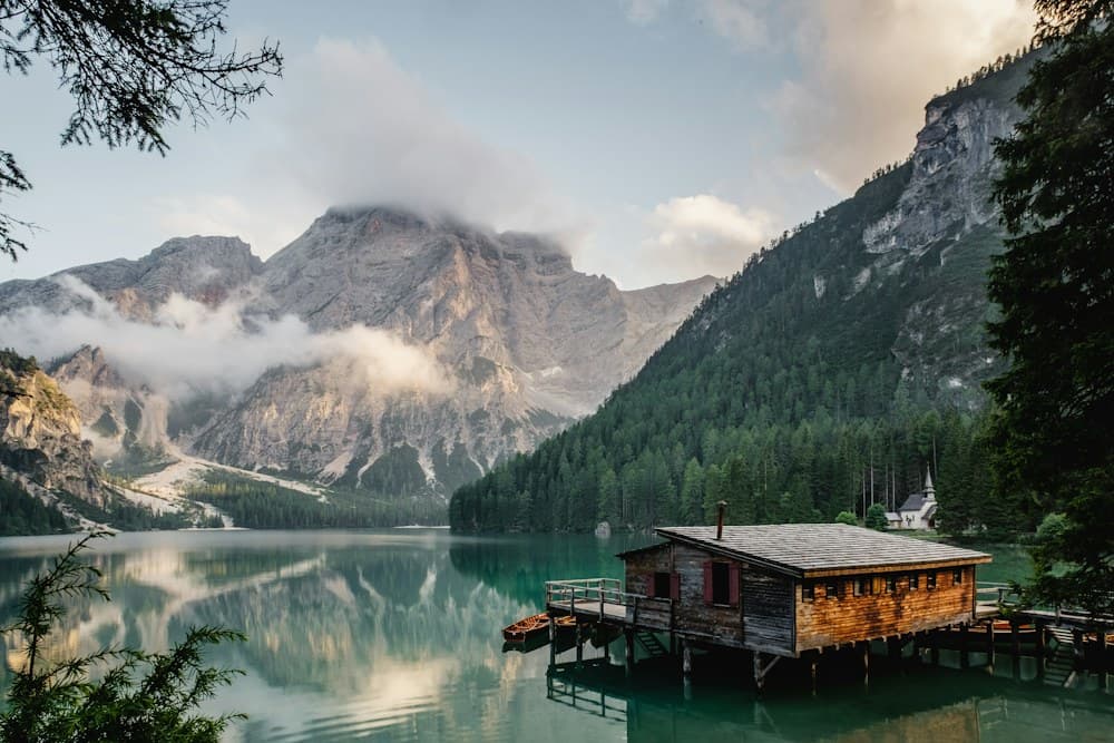 A wooden cabin beside a clear mountain lake
